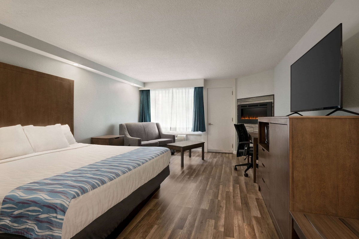 Une chambre d’hôtel avec un grand lit, un bureau, une chaise, un téléviseur à écran plat et une cheminée.