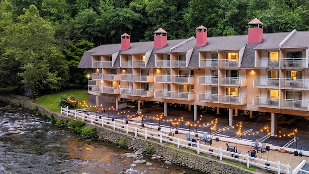 Un hotel de varios pisos con balcones, ubicación a orillas del río y zonas de estar al aire libre.