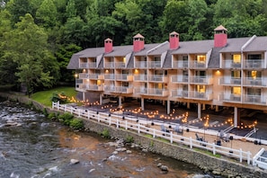 Un hotel de varios pisos con balcones, ubicación a orillas del río y zonas de estar al aire libre.