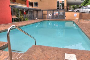 A swimming pool with a tiled deck, metal handrails, and a lifebuoy.