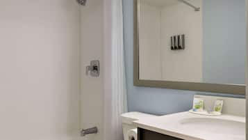 A bathroom with a shower, toilet, sink, and mirror.