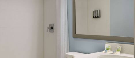 A bathroom with a shower, toilet, sink, and mirror.