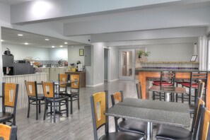 A modern dining area with a kitchen in the background, featuring a bar and seating arrangements.