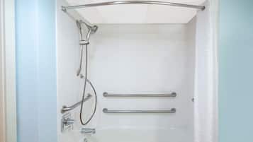 A shower with a grab bar, a handheld showerhead, and a handheld faucet.