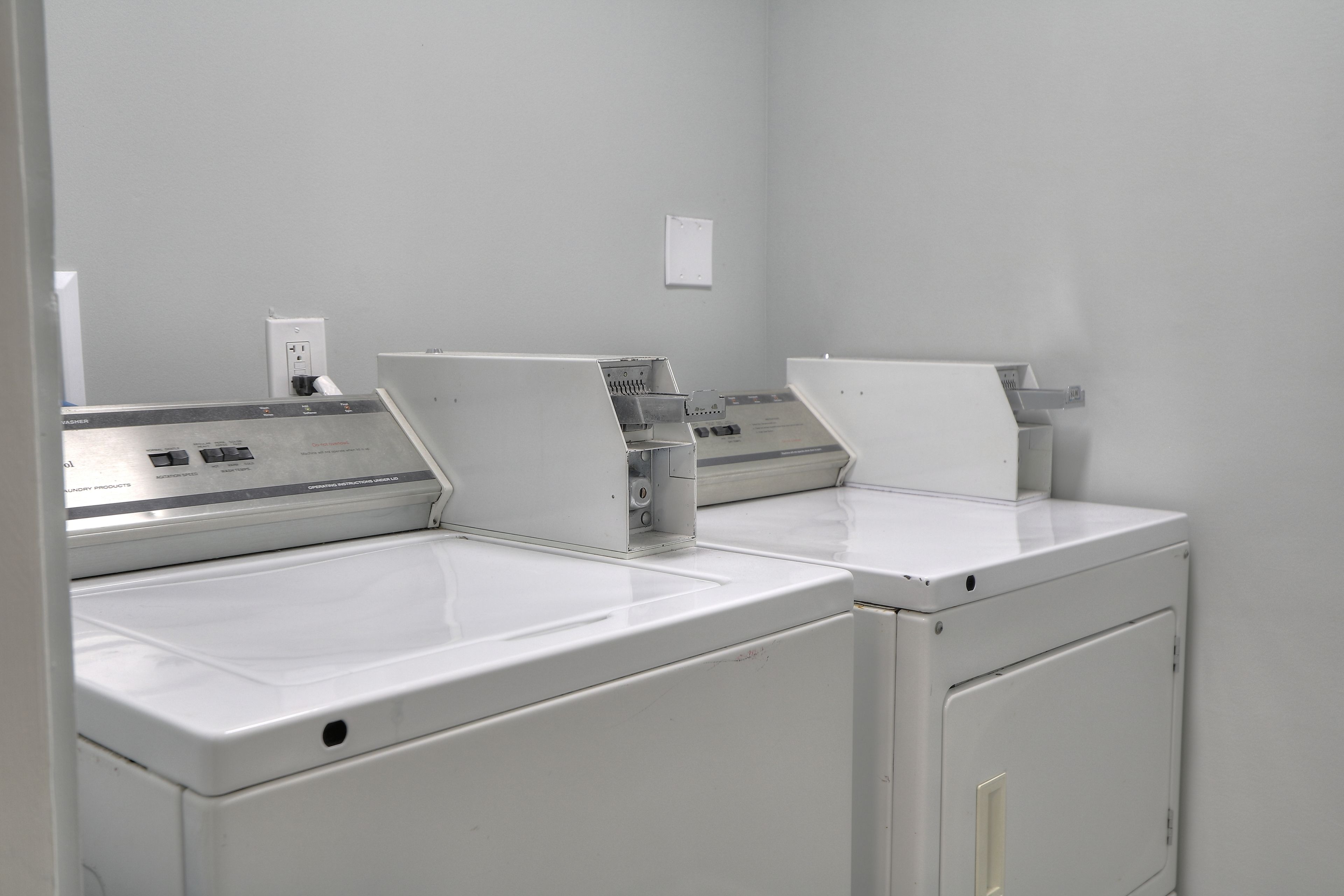 A laundry room with two white washing machines and a dryer.