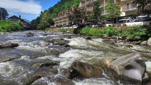 Un hotel con varios balcones, un río frente a él y abundante vegetación.