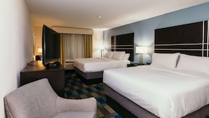A hotel room with two beds, a sofa, a desk, and a TV.