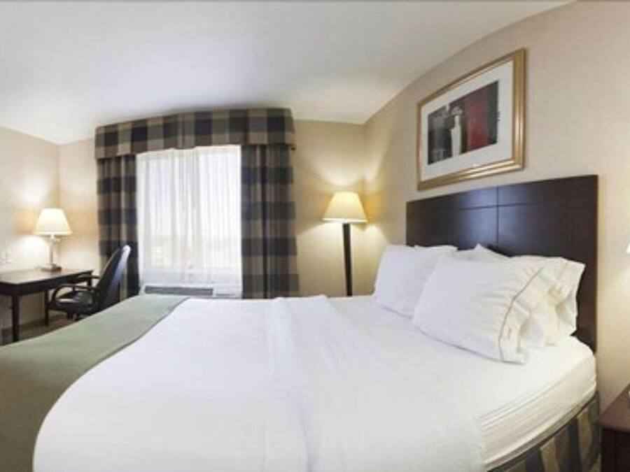 Una habitación de hotel con una cama grande, una silla, un escritorio y una lámpara.