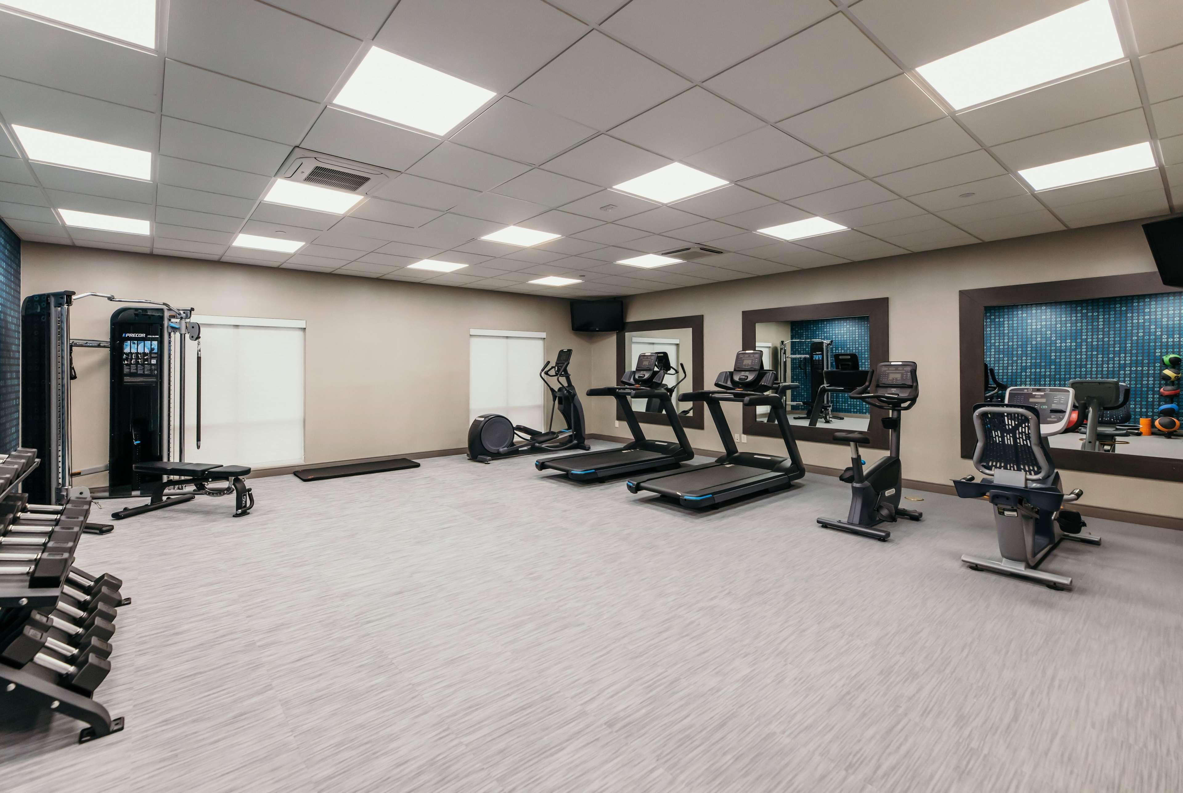 Un gimnasio con cintas de correr, bicicletas estáticas y máquinas de pesas.