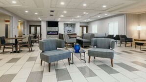 A spacious lobby with modern furniture, a patterned wall, and a tiled floor.