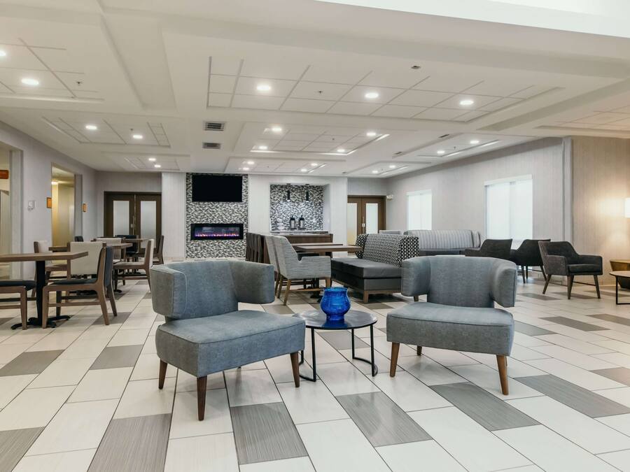 Een ruime lobby met modern meubilair, een behang met patroon en een betegelde vloer.