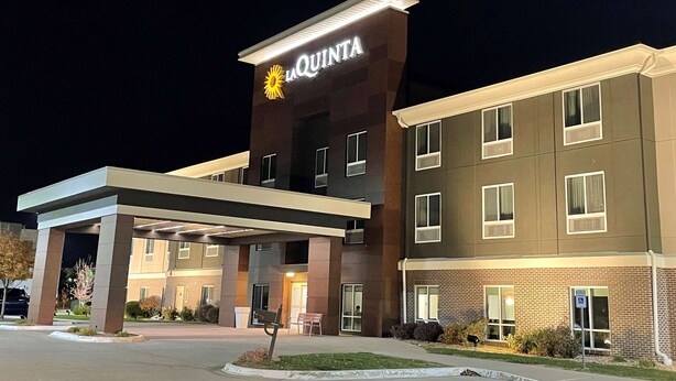A La Quinta hotel with a modern design, featuring a prominent sign, a covered entrance, and a brick facade.