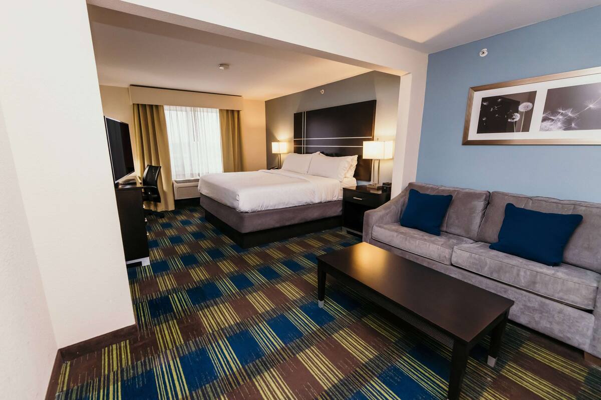Een hotelkamer met een bed, een bank, een salontafel en een televisie.