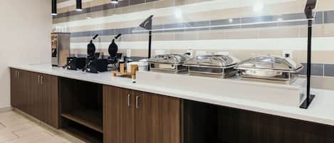 Una cocina moderna con una encimera larga, electrodomésticos de acero inoxidable y un salpicadero de azulejos a rayas.