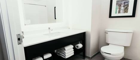 A modern bathroom with a white sink, black vanity, and a toilet.