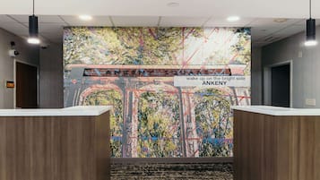 Un área de recepción con un mural abstracto y lleno de color, un cartel que dice "ANKENY SQUARE" y el lema "despierta del lado brillante".