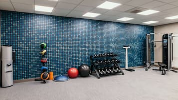 A gym with exercise equipment, a wall with circular patterns, and a ceiling with square lights.