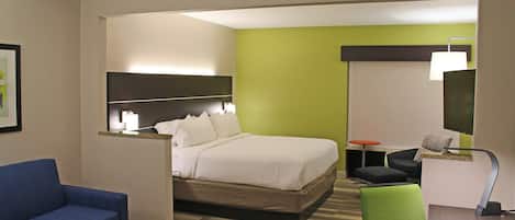 A hotel room with a bed, a desk, a chair, a sofa, and a mirror.