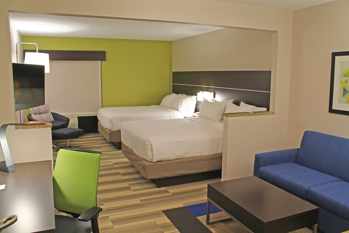 Een hotelkamer met twee bedden, een bureau, een stoel, een bank en een lamp.