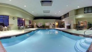 An indoor swimming pool with a clear view of the pool area, including the pool's edge, a set of stairs leading into the pool, and a few lounge chairs and tables around the pool. - Holiday Inn Express Hotel & Suites Cape Girardeau I-55 by IHG (Cape Girardeau)