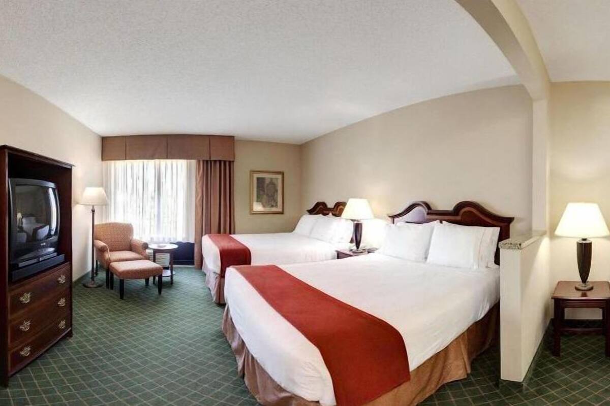 Een hotelkamer met twee bedden, een televisie, een bureau en een stoel.
