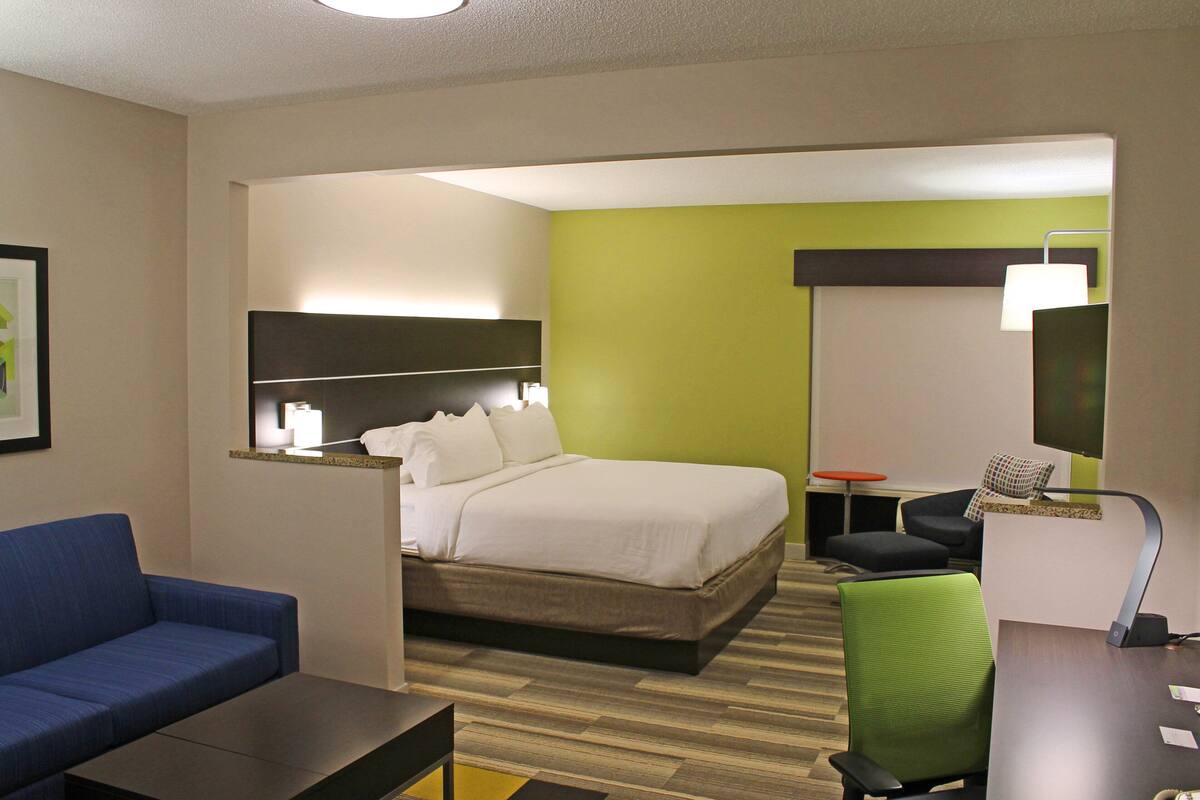 Een hotelkamer met een bed, een blauwe bank, een bureau en een groene stoel.