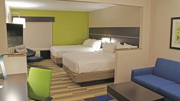 A hotel room with two beds, a desk, a chair, a sofa, and a framed picture on the wall.