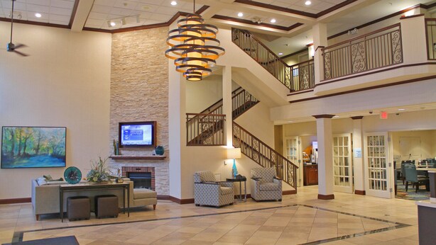 A spacious lobby with a fireplace, comfortable seating, a staircase, and a large chandelier. - Holiday Inn Express Hotel & Suites Cape Girardeau I-55 by IHG (Cape Girardeau)