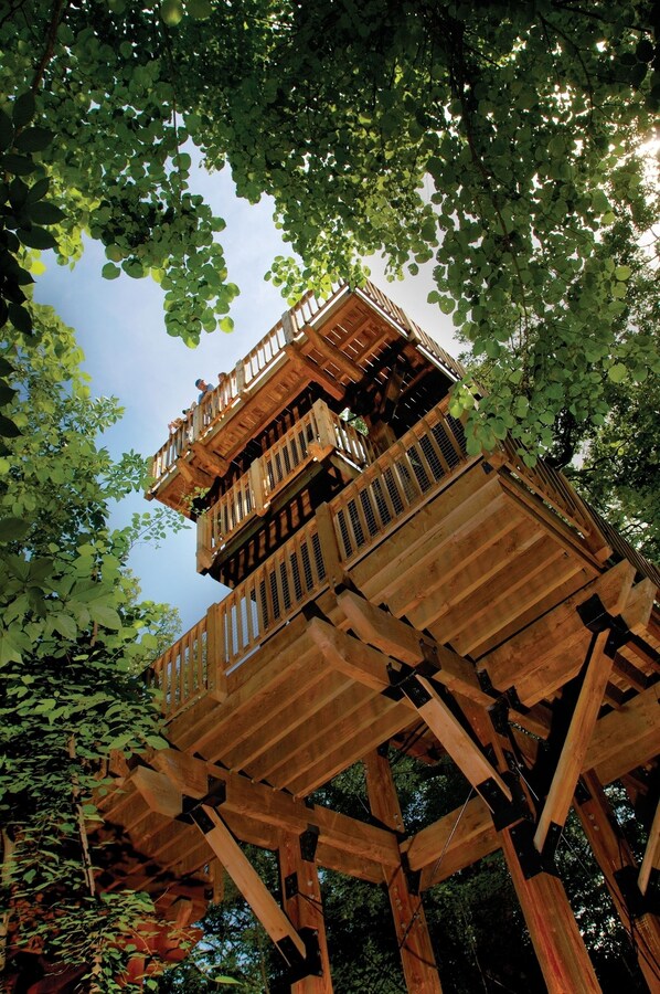 A multi-level wooden structure with balconies, surrounded by dense foliage. - Lied Lodge & Conference Center (Nebraska City)