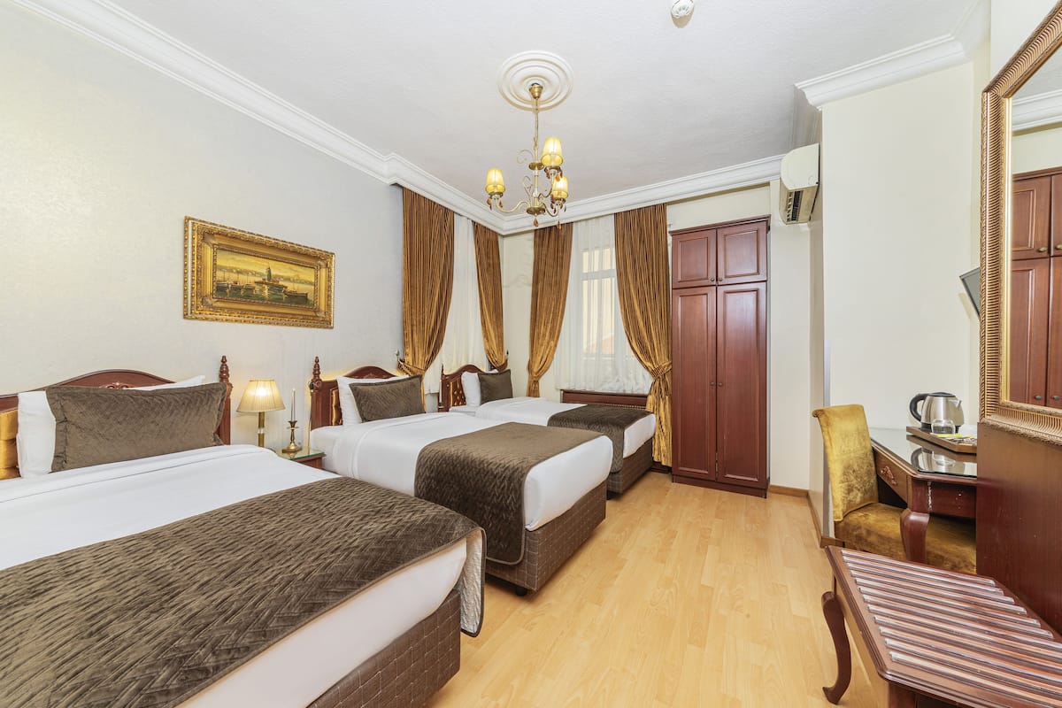 A hotel room with two beds, a desk, a chair, a mirror, and a chandelier.