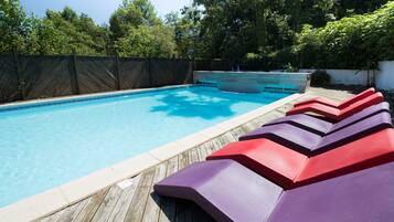 Una piscina amb terrassa de fusta i gandules de colors.