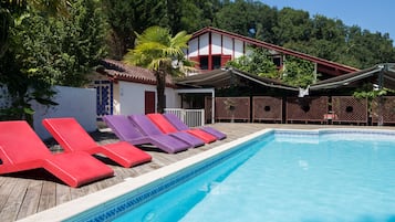 Una piscina al aire libre de temporada, sillones reclinables de piscina
