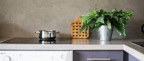 A kitchen with a stove, a pot, a potted plant, and a wooden utensil holder.