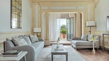 A spacious living room with two grey sofas, a coffee table, and a side table with a lamp.