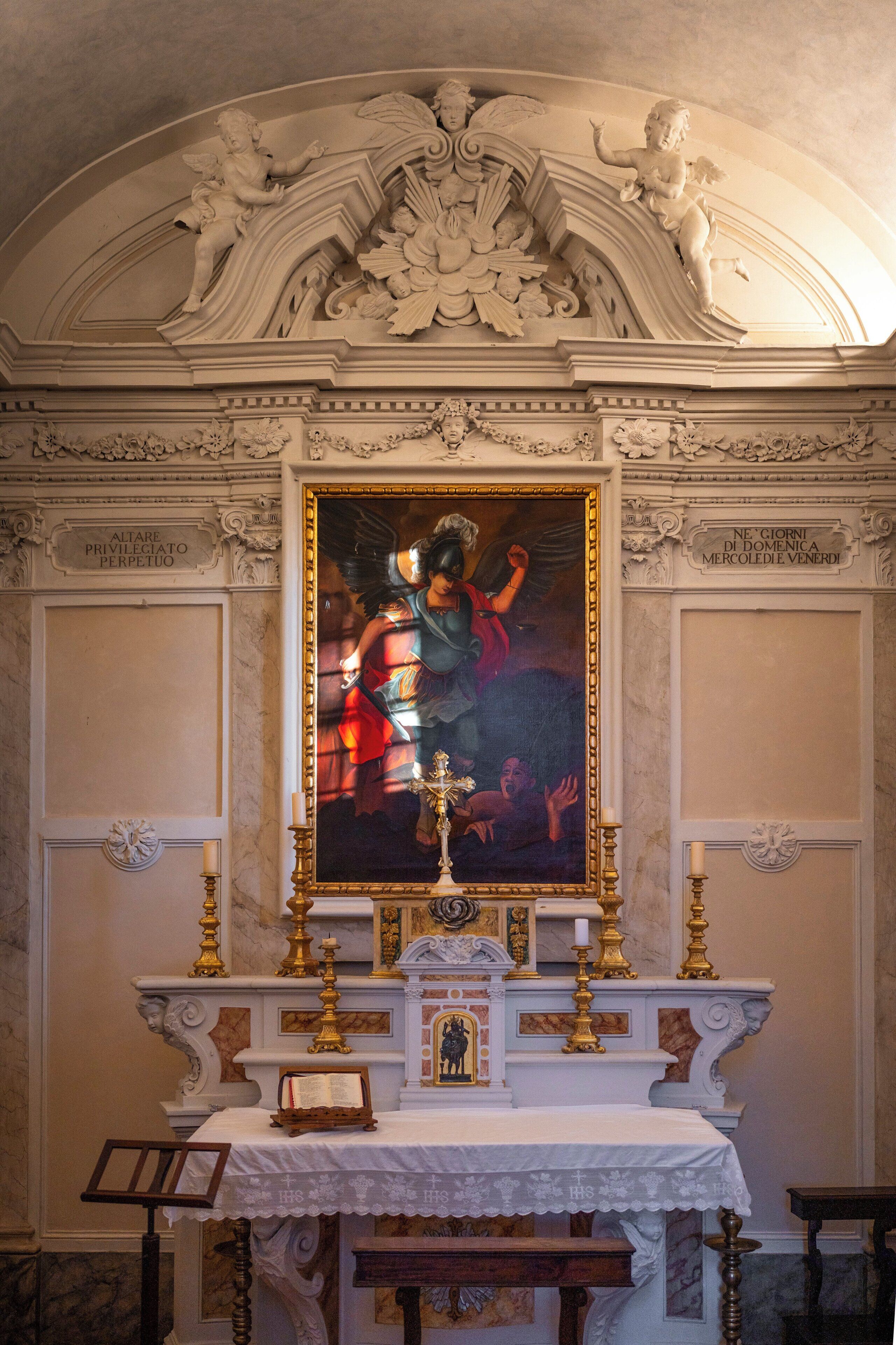 An ornate altar with a religious painting, a crucifix, and candles.