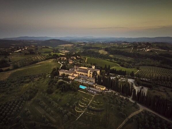 Vista aérea de una finca histórica con varias construcciones, piscina y viñedos en terrazas.
