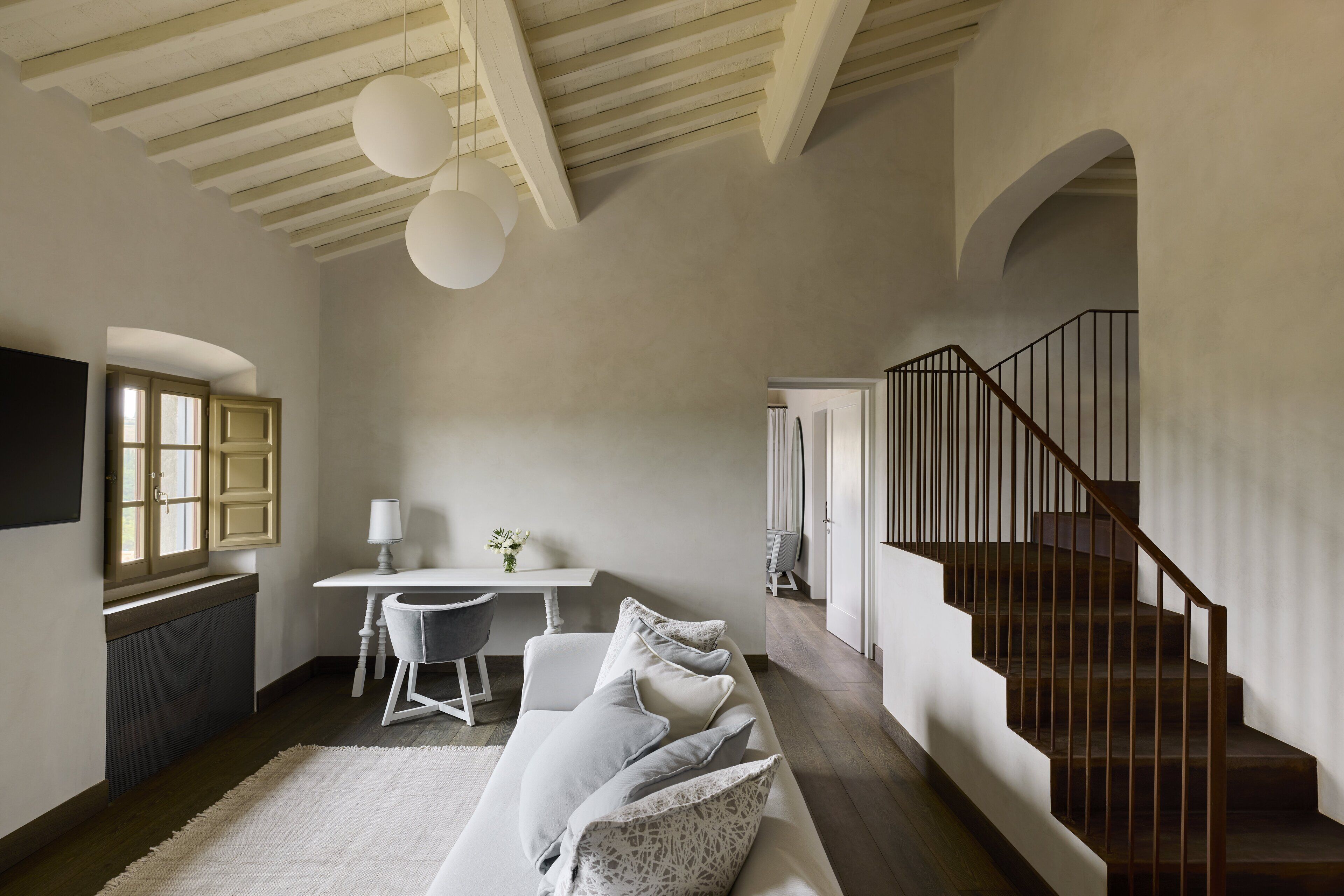 Um interior moderno com escada, um sofá branco e uma área de jantar.