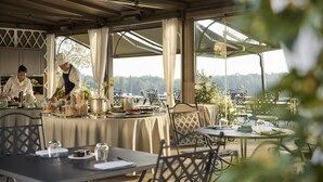 An outdoor dining area with tables and chairs, a chef preparing food, and a scenic view in the background. - COMO Castello Del Nero (Barberino Tavarnelle)