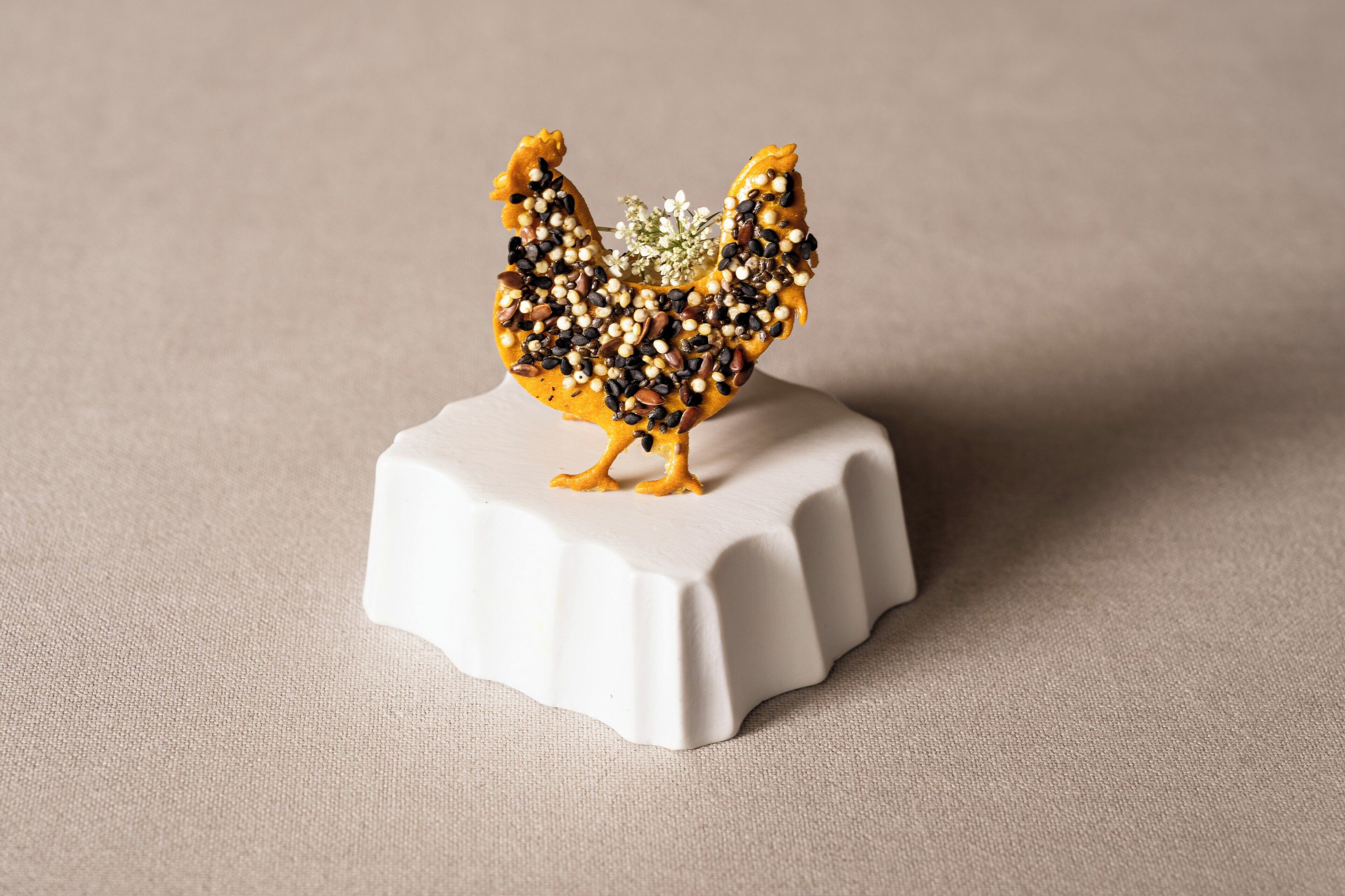 A decorative rooster figurine on a white pedestal.