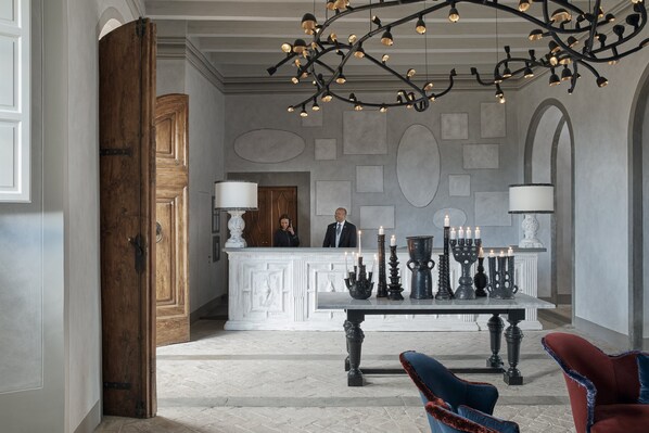 A grand lobby with a reception desk, elegant chandeliers, and classic furniture. - COMO Castello Del Nero (Barberino Tavarnelle)