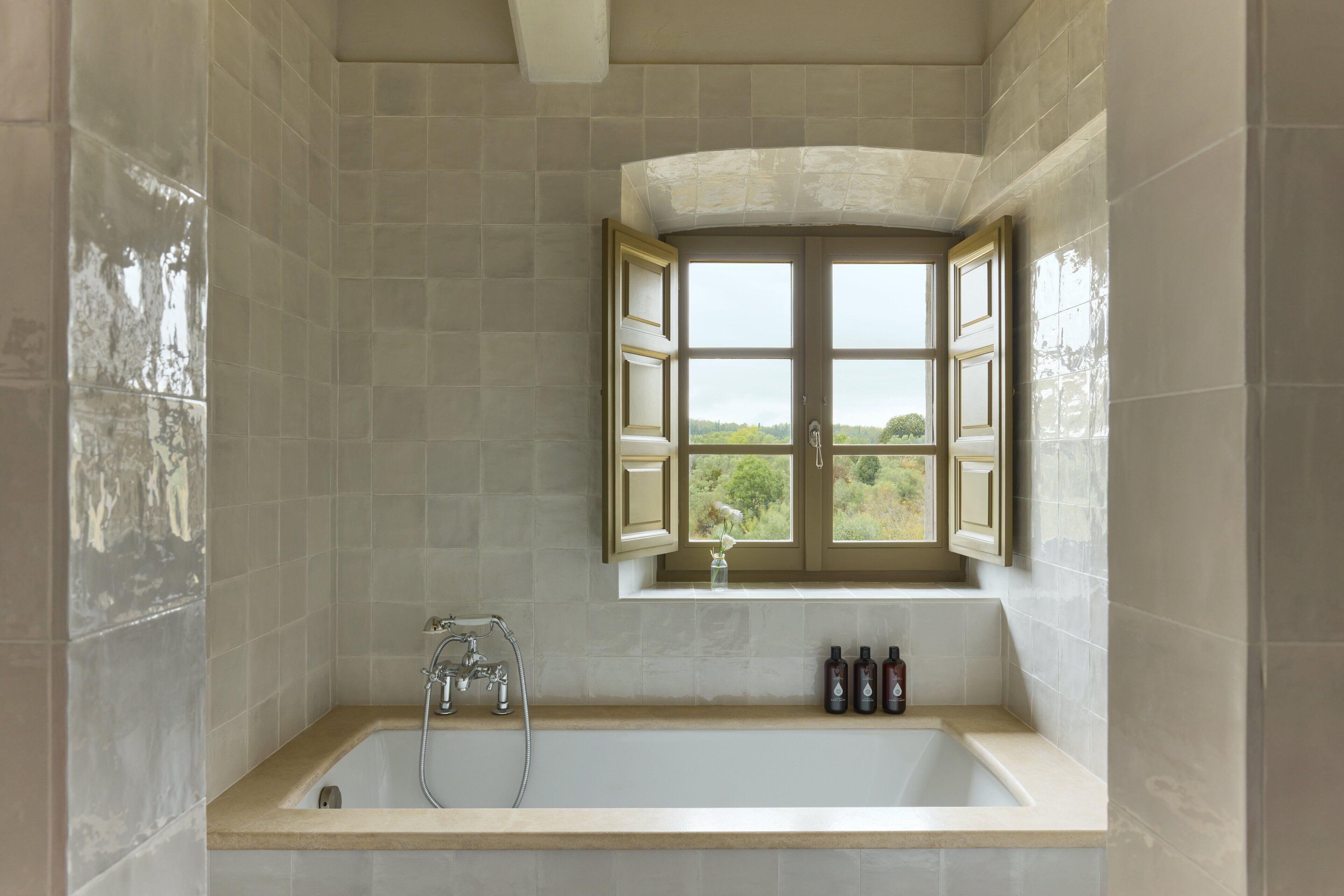 Un baño con bañera, una ventana con vistas y un estante con artículos de aseo.