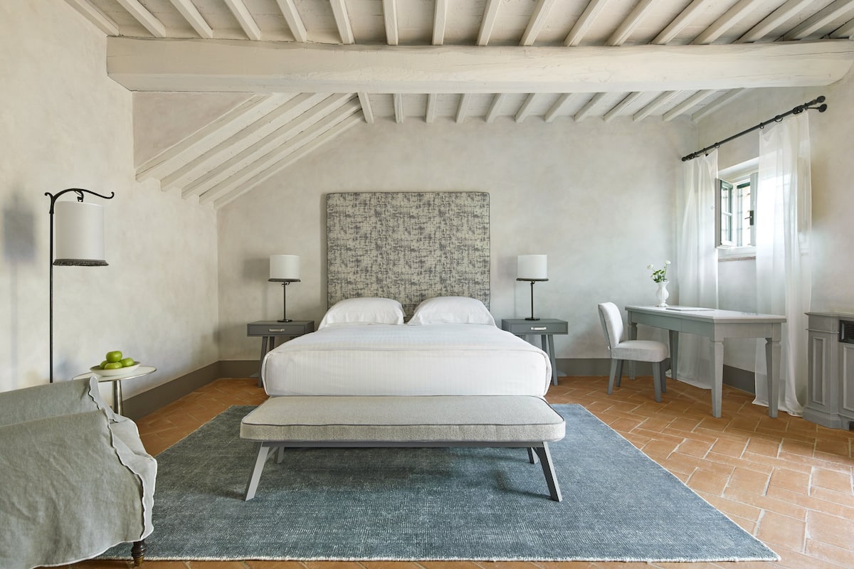 Un dormitorio con cama, mesitas de noche, un escritorio y una silla.