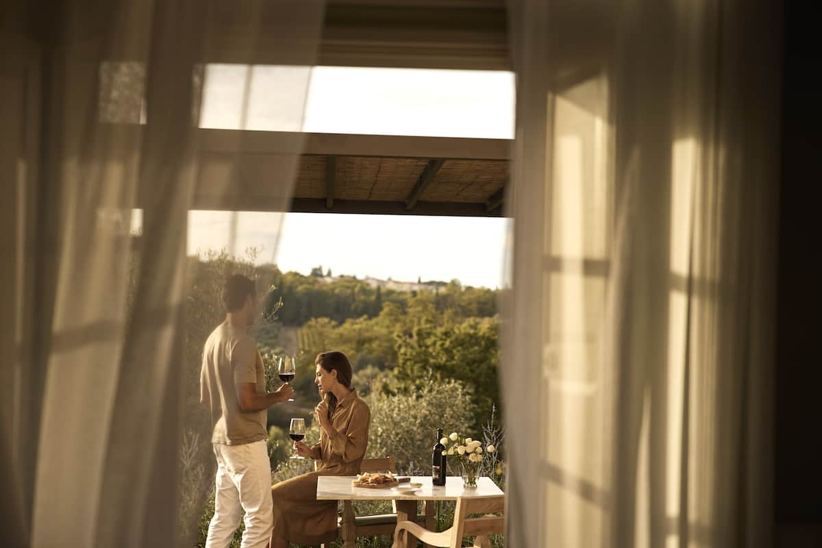 Una pareja cenando en una mesa al aire libre con una vista panorámica de un viñedo.