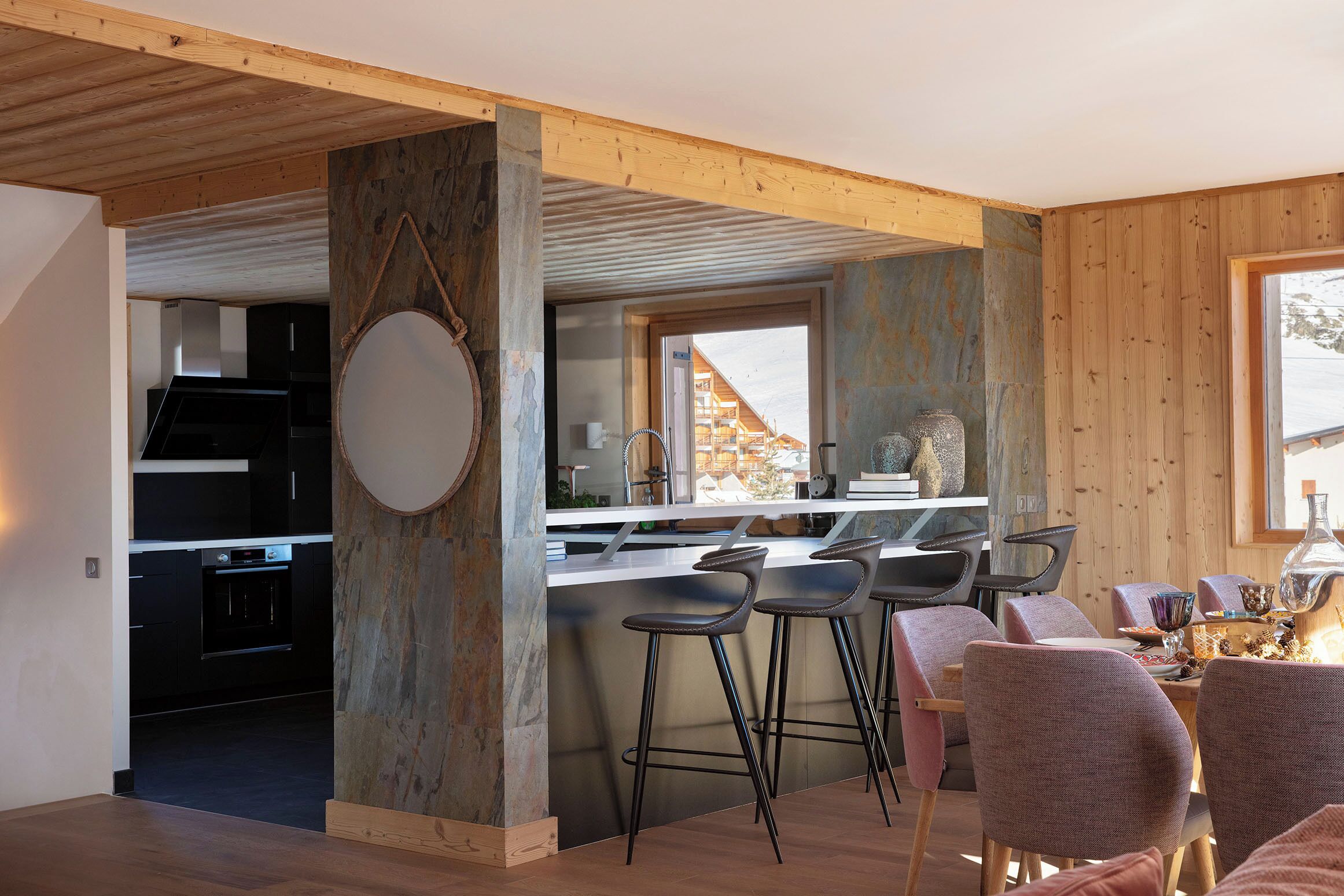 A modern kitchen with a central island, bar stools, and a view of the outside.