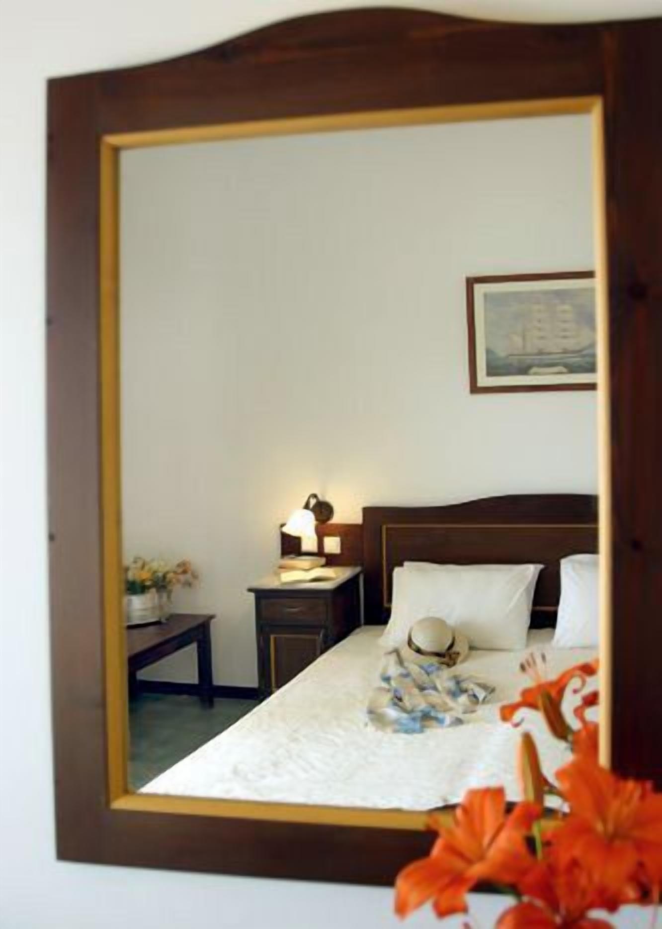 A bedroom with a bed, bedside table, lamp, and a framed picture on the wall.