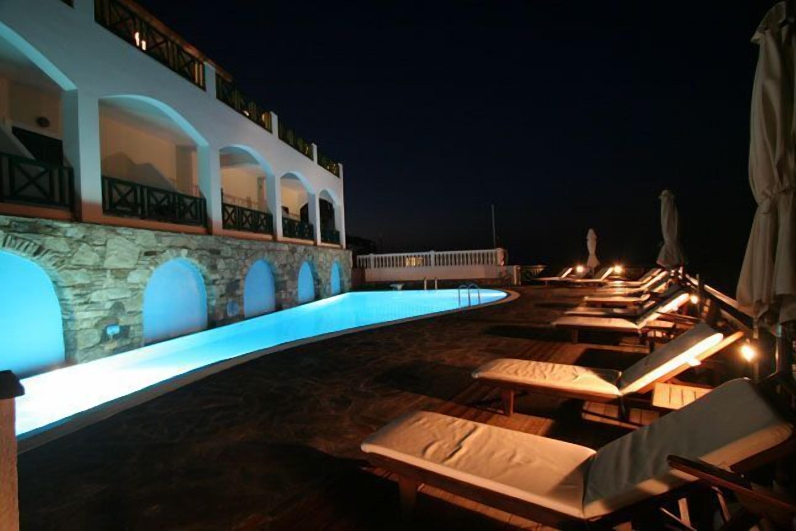 A pool area with lounge chairs and a stone wall.