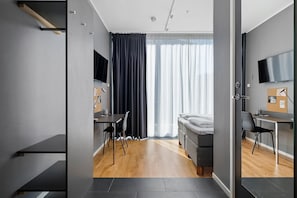 A modern hotel room with a bed, a desk, a chair, a TV, and a large window with curtains. - Aiden by Best Western Stockholm Arlanda Airport (Arlandastad)