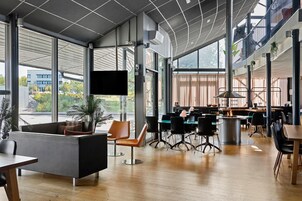 A spacious indoor area with high ceilings, large windows, and a variety of seating arrangements including tables and chairs.