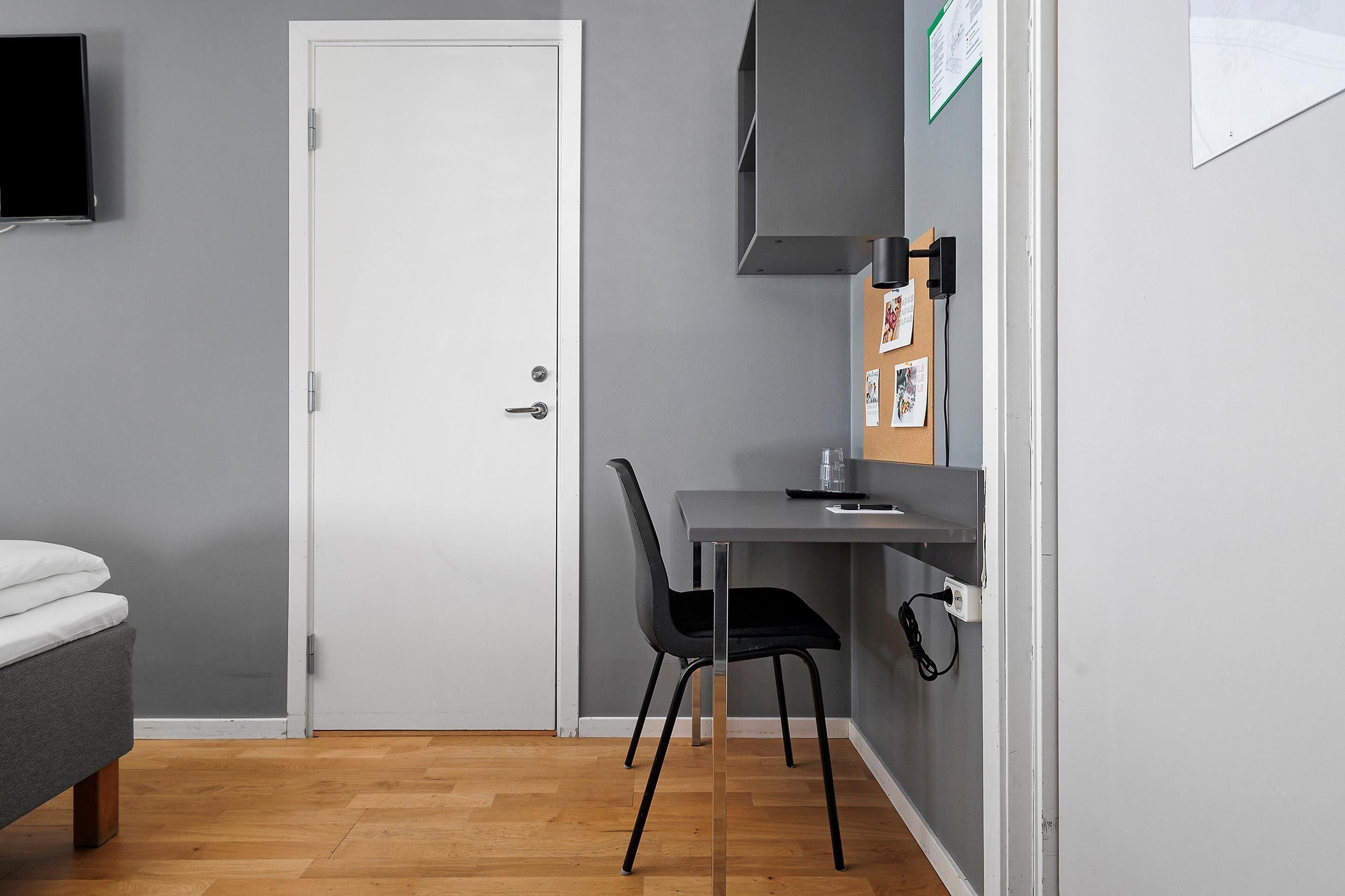 Une petite pièce, de taille modeste, comprenant un lit, un bureau et une chaise.