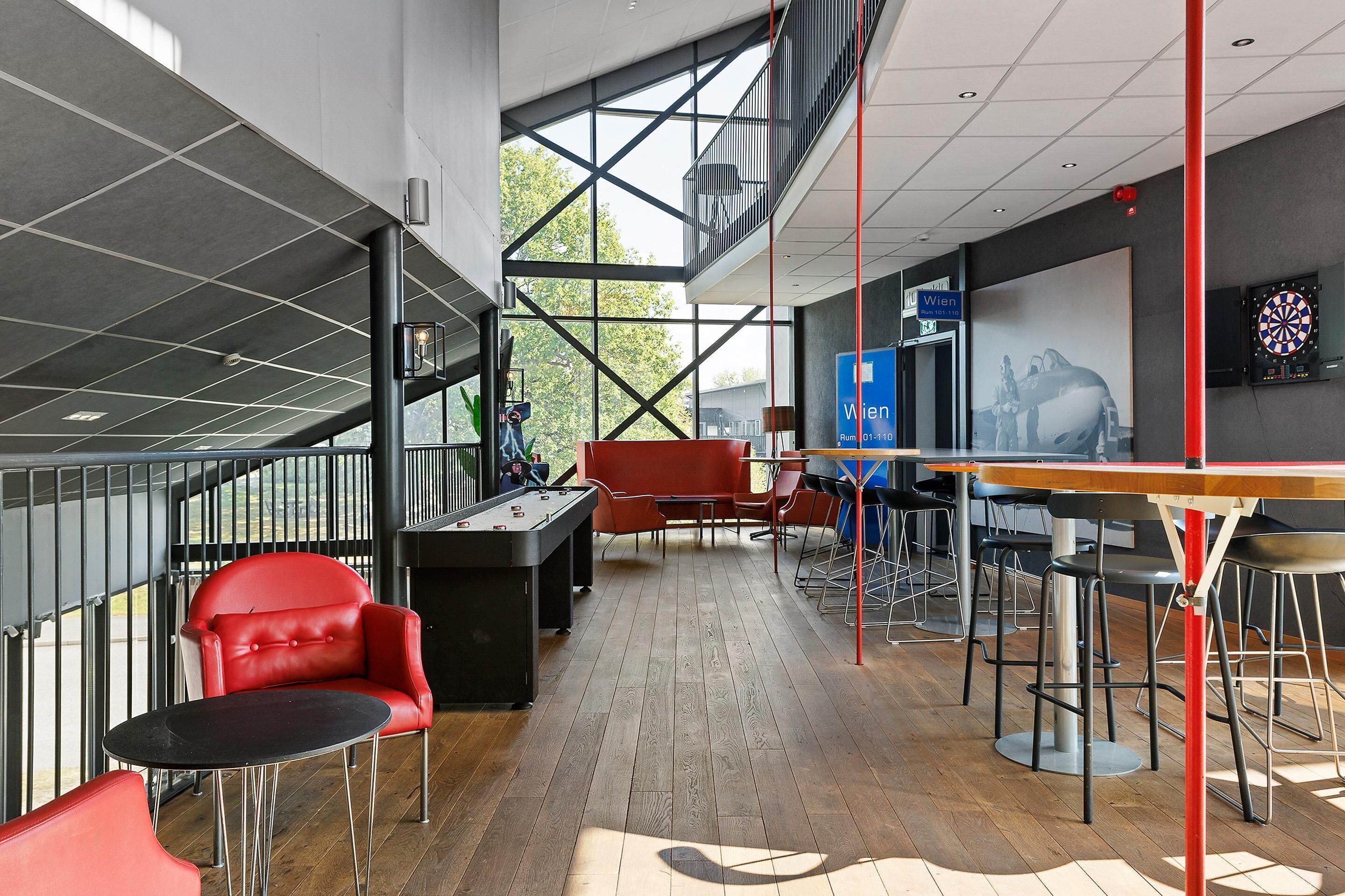 An indoor space with a pool table, red chairs, and a dartboard.